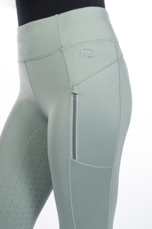 Side view of sage green equestrian riding tights with same colored embroidered HKM logo on hip