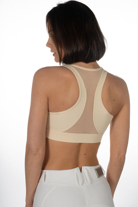 Model showing the back of a tan sports bra with mesh