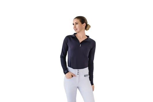 Woman wearing a black long-sleeve top and white riding pants on a white background