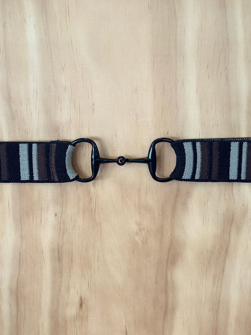 Black patterned elastic belt with a dark buckle that looks like a horse's snaffle bit