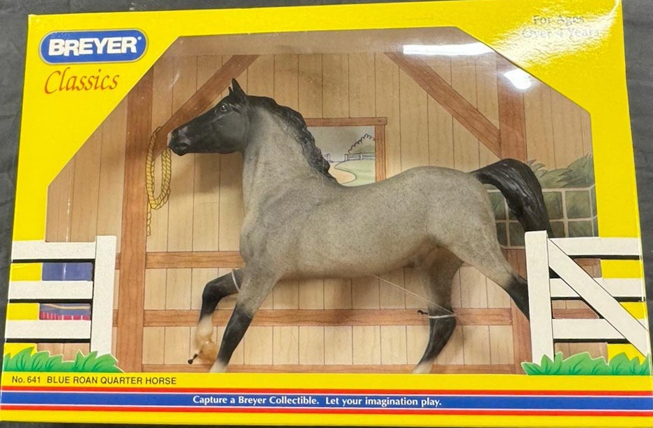 Breyer Classics Blue Roan Quarter Horse toy model in its original yellow packaging box, showing the gray horse figure standing in front of a wooden stable backdrop.