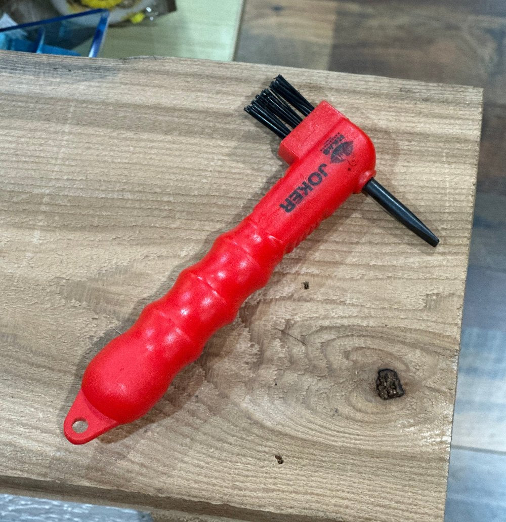 Hoof pick with molded handle, a thin row of bristles opposite a pick that resembles a flat screwdriver