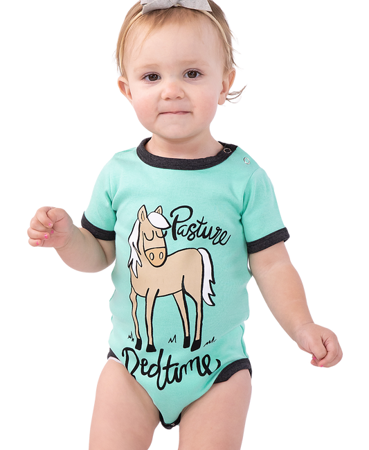 Baby wearing a mint green onesie with a horse graphic and text ("Pasture Bedtime") on a white background