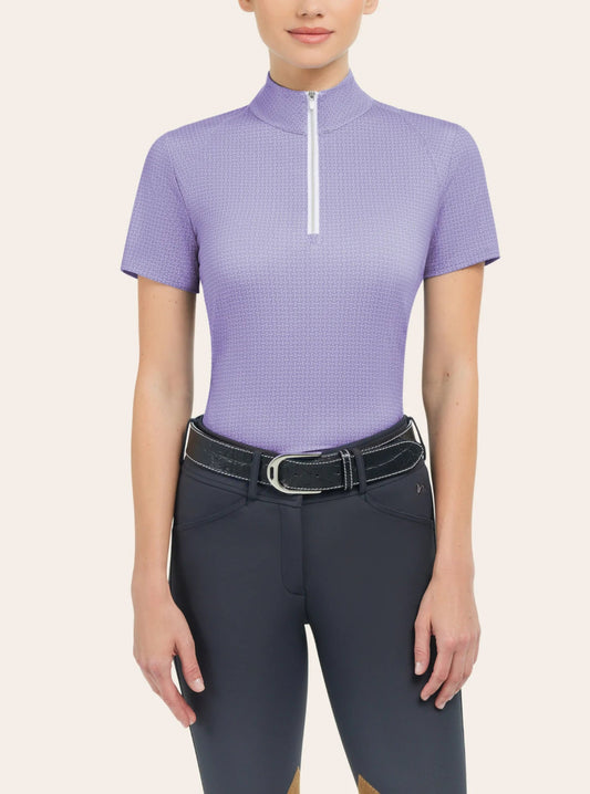Model wearing lilac colored quarter zip short sleeve shirt with horse bit pattern throughout shirt.