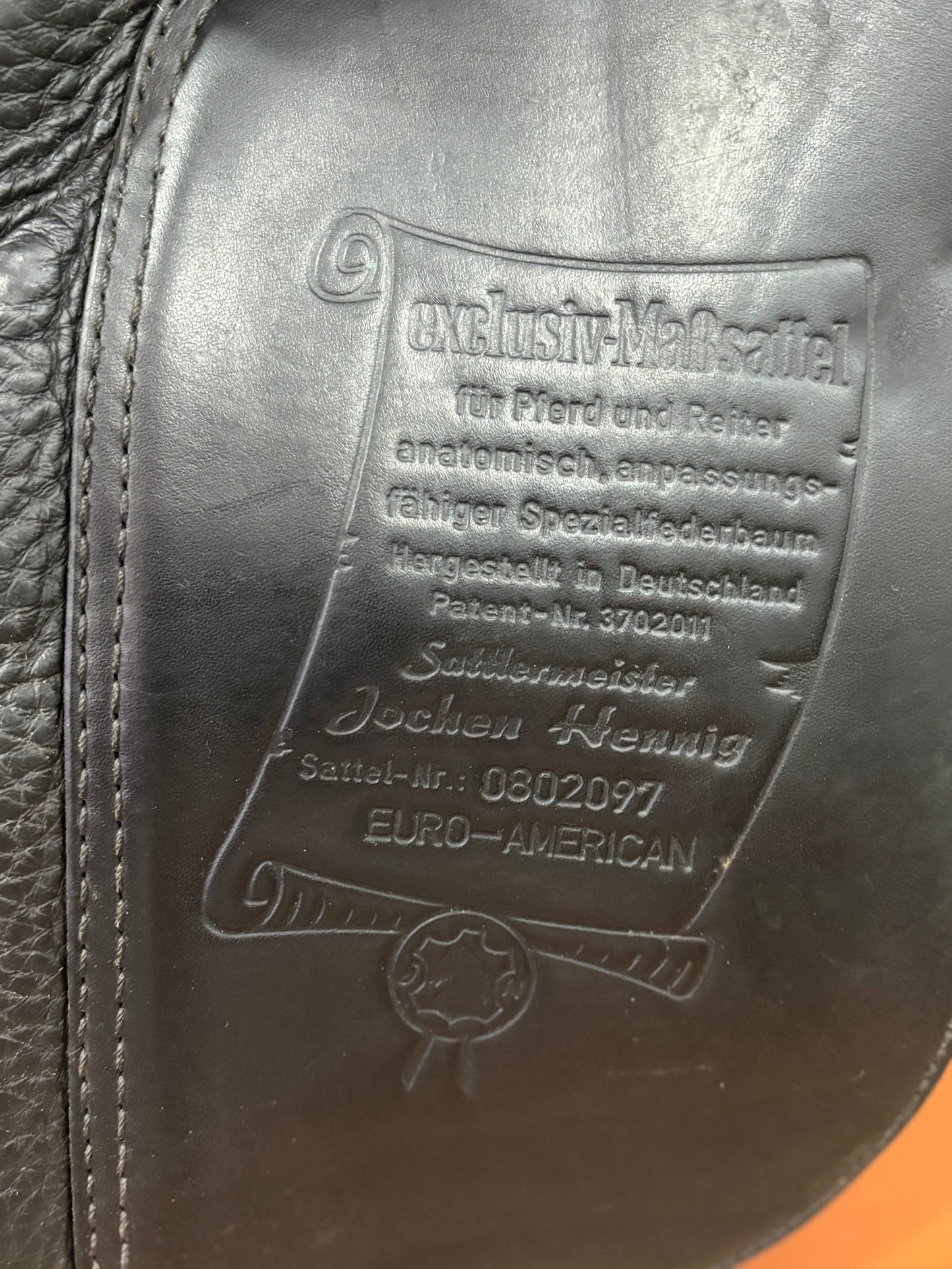Close up of the underflap of a black leather saddle showing the embossed stamp.