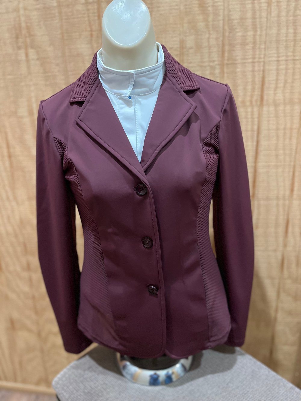 Mannequin modeling a plum colored, 3 button equestrian show coat