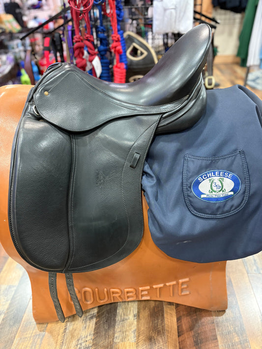 Black Dressage saddle shown on a stand along with a navy Schleese branded saddle cover