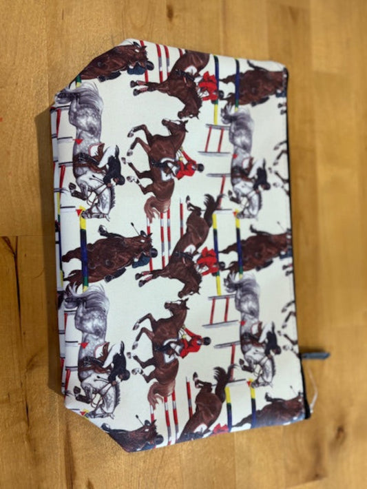 Cosmetic pouch with a print of multiple horses going over jumps with their riders