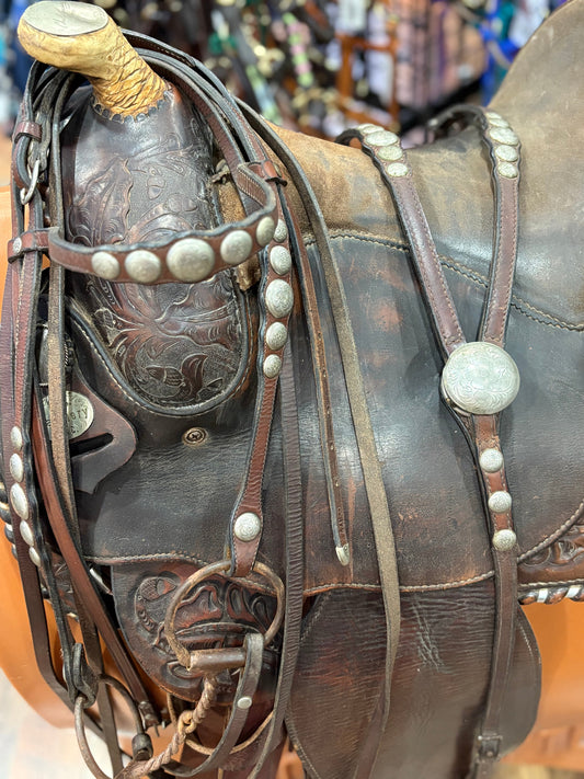Decorated western headstall and matching breastplate shown draped on a western saddle