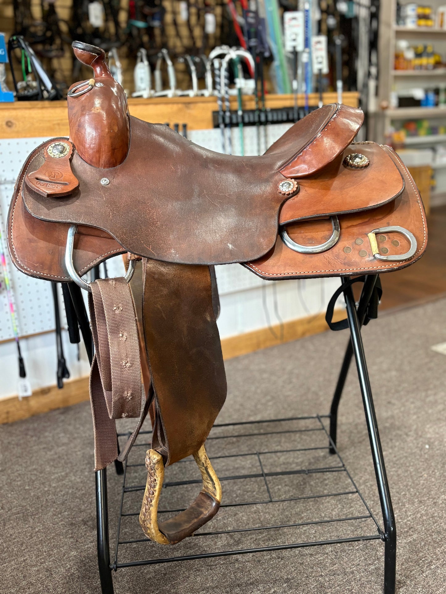 Brown leather saddle on a stand in a store setting