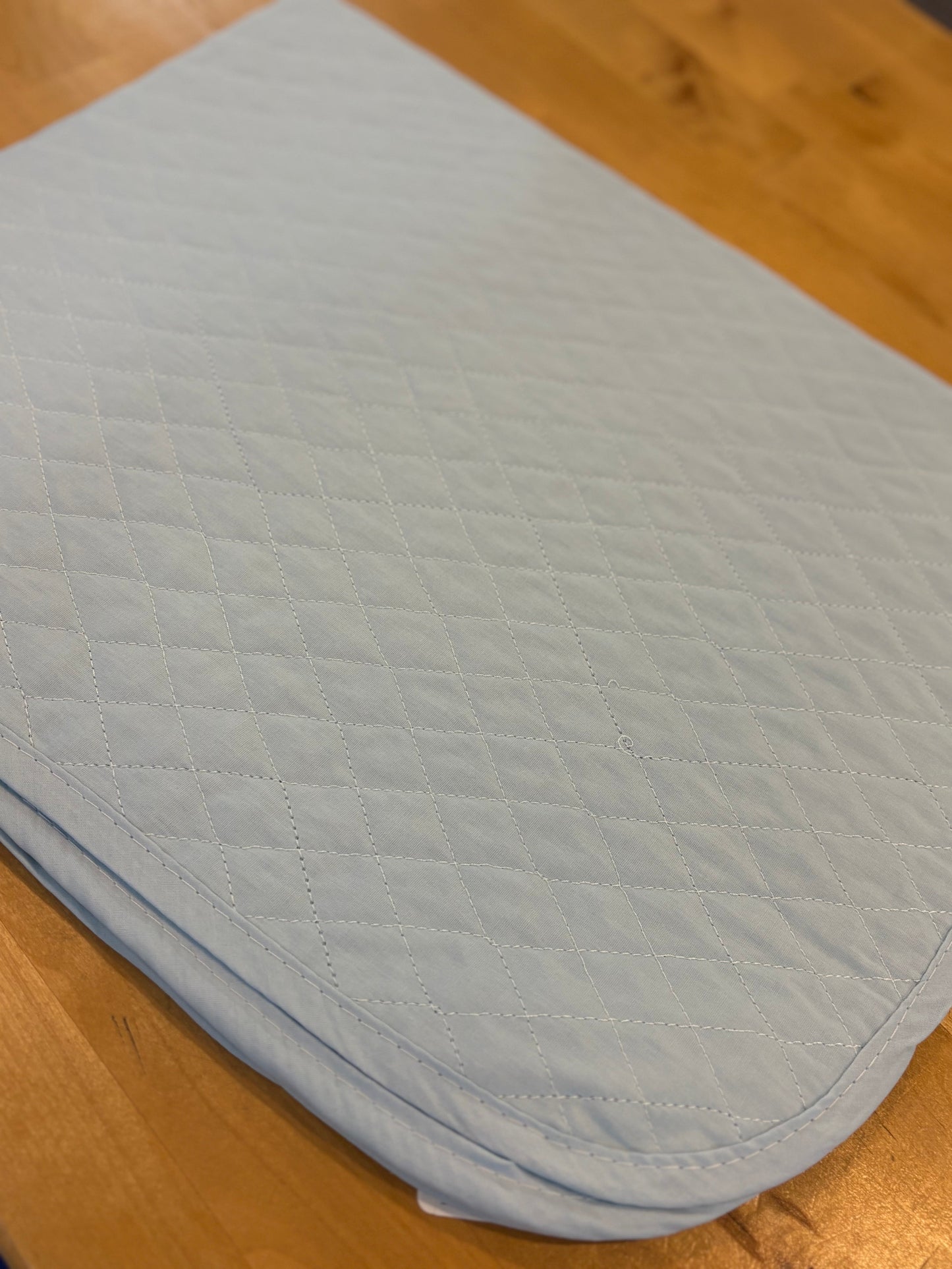 Light blue quilted saddle pad on a wooden surface
