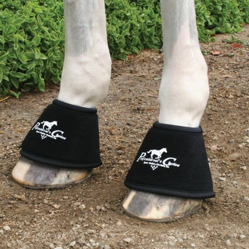 Black bell boots with white Professional's Choice logo shown on a pair of white horse legs