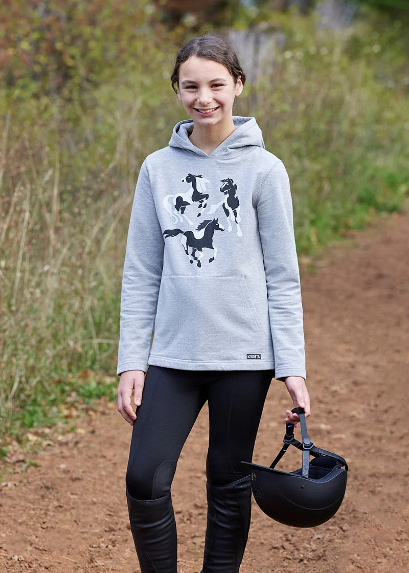 Young equestrian girl wearing a grey hoodie sweatshirt with black and white frolicking horses printed on the front