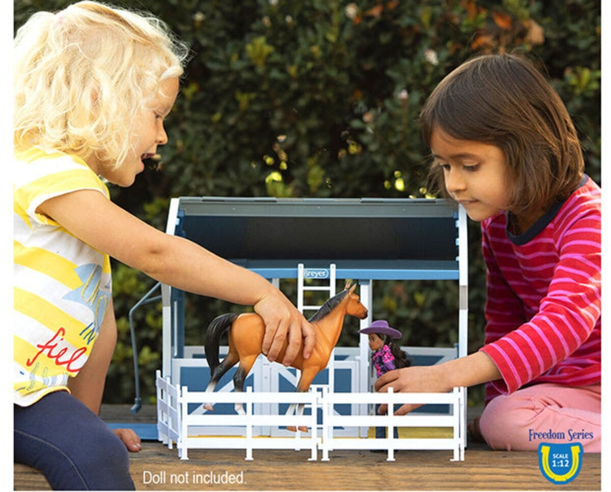 two young girls playing with their horse and barn toys