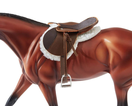 Model horse with a brown leather saddle and white wool padding on a white background