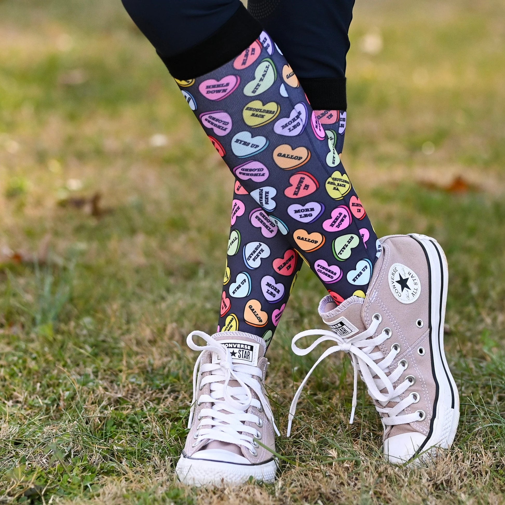 Colorful heart-patterned boot socks with white high-top sneakers on grass