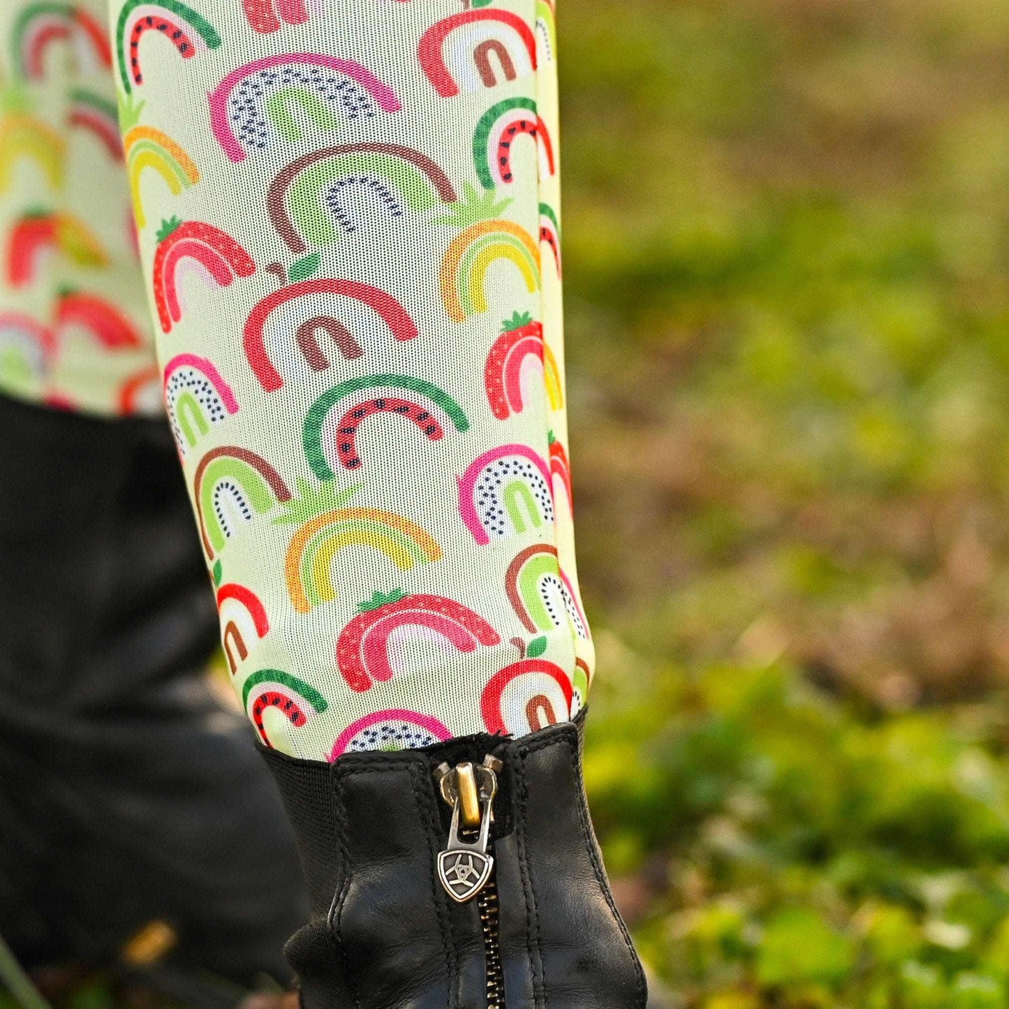 Colorful rainbow-patterned knee socks on a person's legs with a blurred green background.