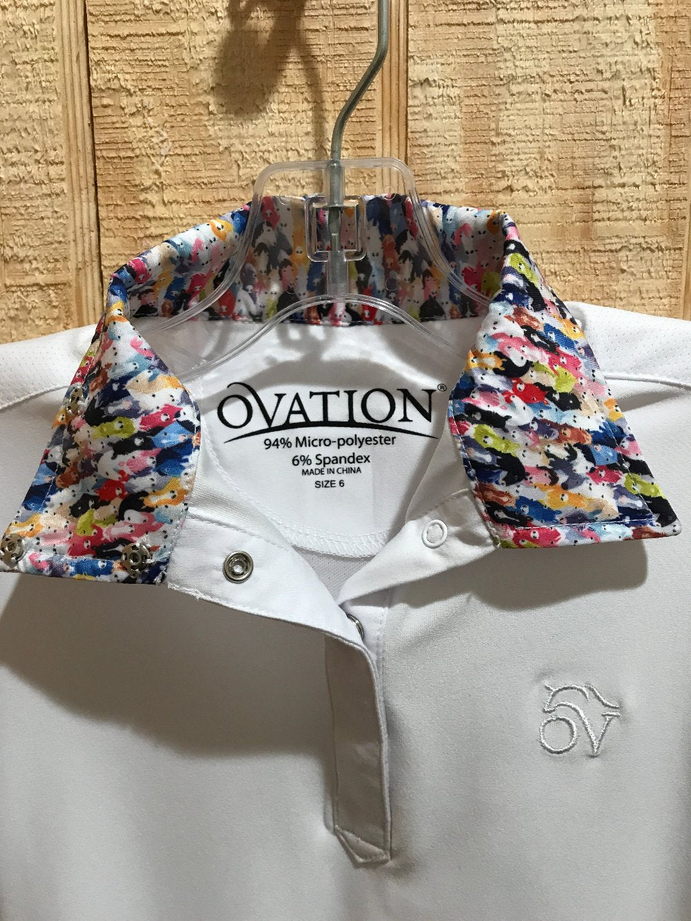 close up of the inside collar of an equestrian show shirt showing a pattern of colorful horse heads