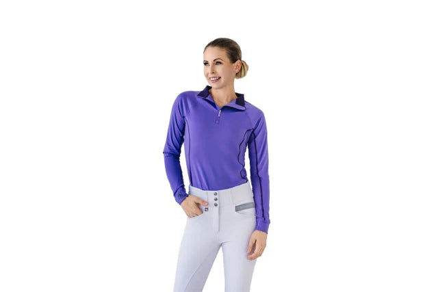 Woman wearing a purple long-sleeve top and white pants on a white background