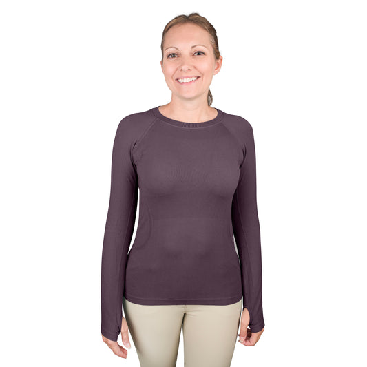 Equestrian woman wearing a long sleeve pluot colored seamless top with thumb holes.