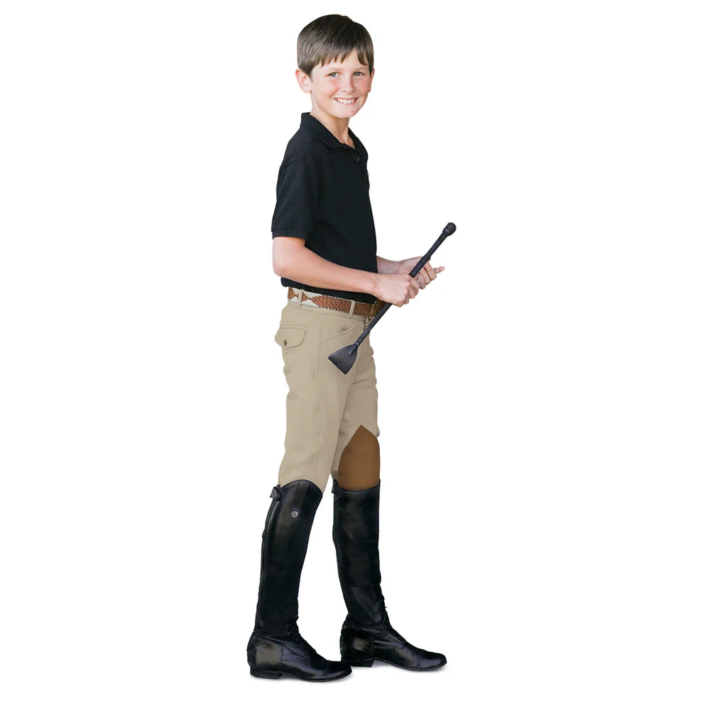 Young equestrian boy dressed to ride in a navy polo, tan breeches and black tall boots