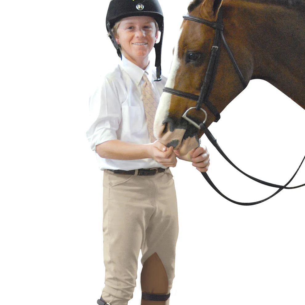 Young equestrian boy dressed for a show holding his bridled horse