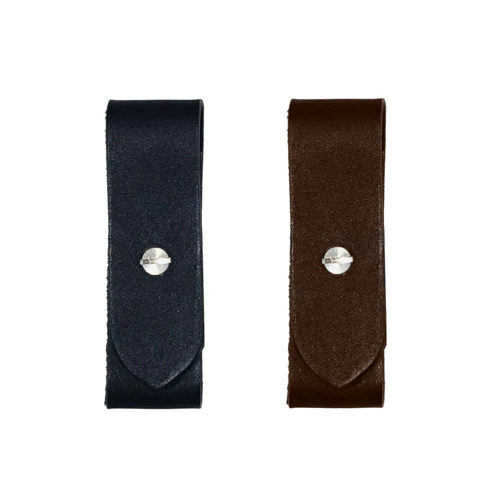 One black, one brown leather breakaway fuses with silver screws on a white background