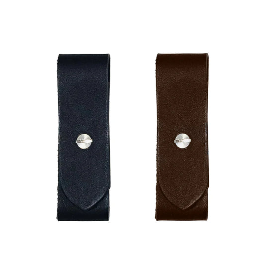 One black, one brown leather breakaway fuses with silver screws on a white background