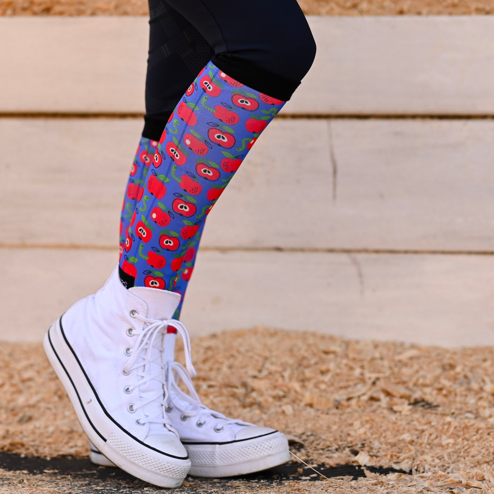 Colorful patterned knee-high socks with white sneakers on a neutral background