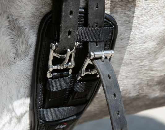 close up of buckles of a black dressage girth