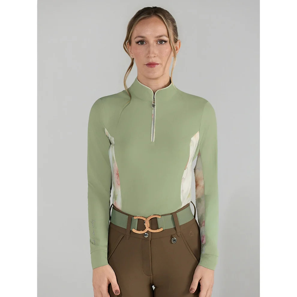 Woman wearing a green equestrian top with floral sleeves on a gray background