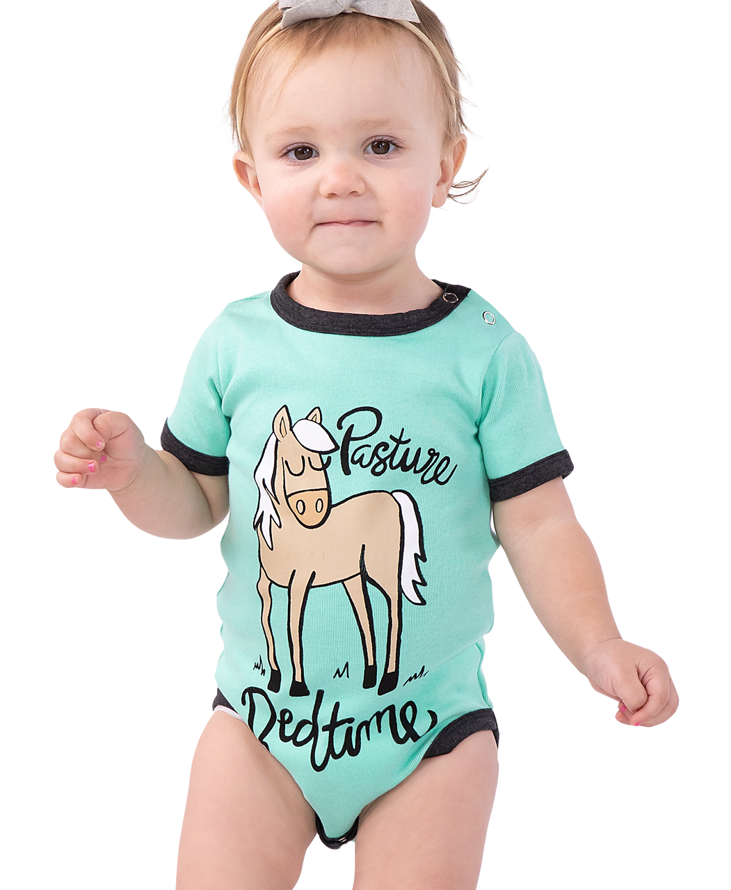 Baby wearing a mint green onesie with a horse graphic and text ("Pasture Bedtime") on a white background