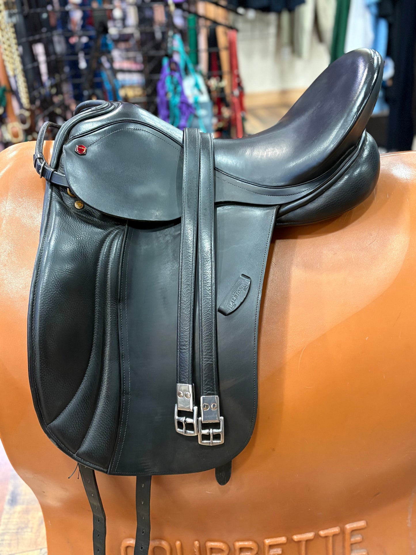 Black leather saddle on a horse mannequin with a blurred background