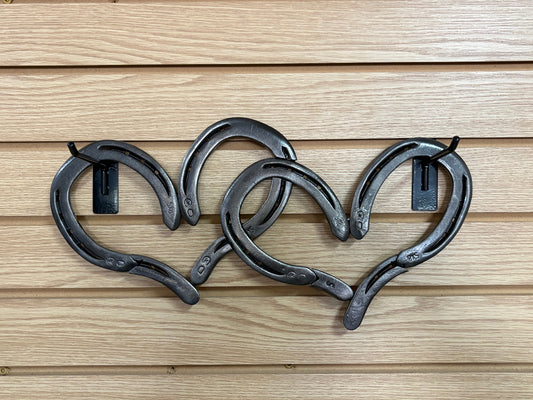 Heart-shaped wall art made of black metal horseshoes on a wooden background