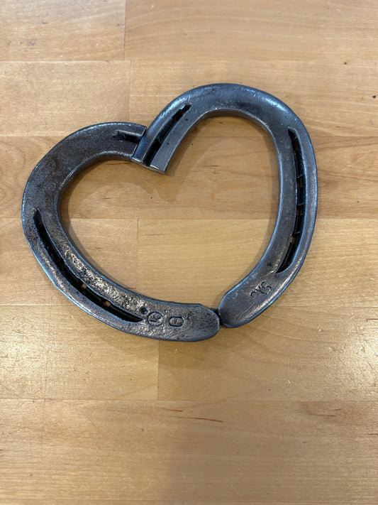 Heart-shaped metal horseshoe on a wooden surface
