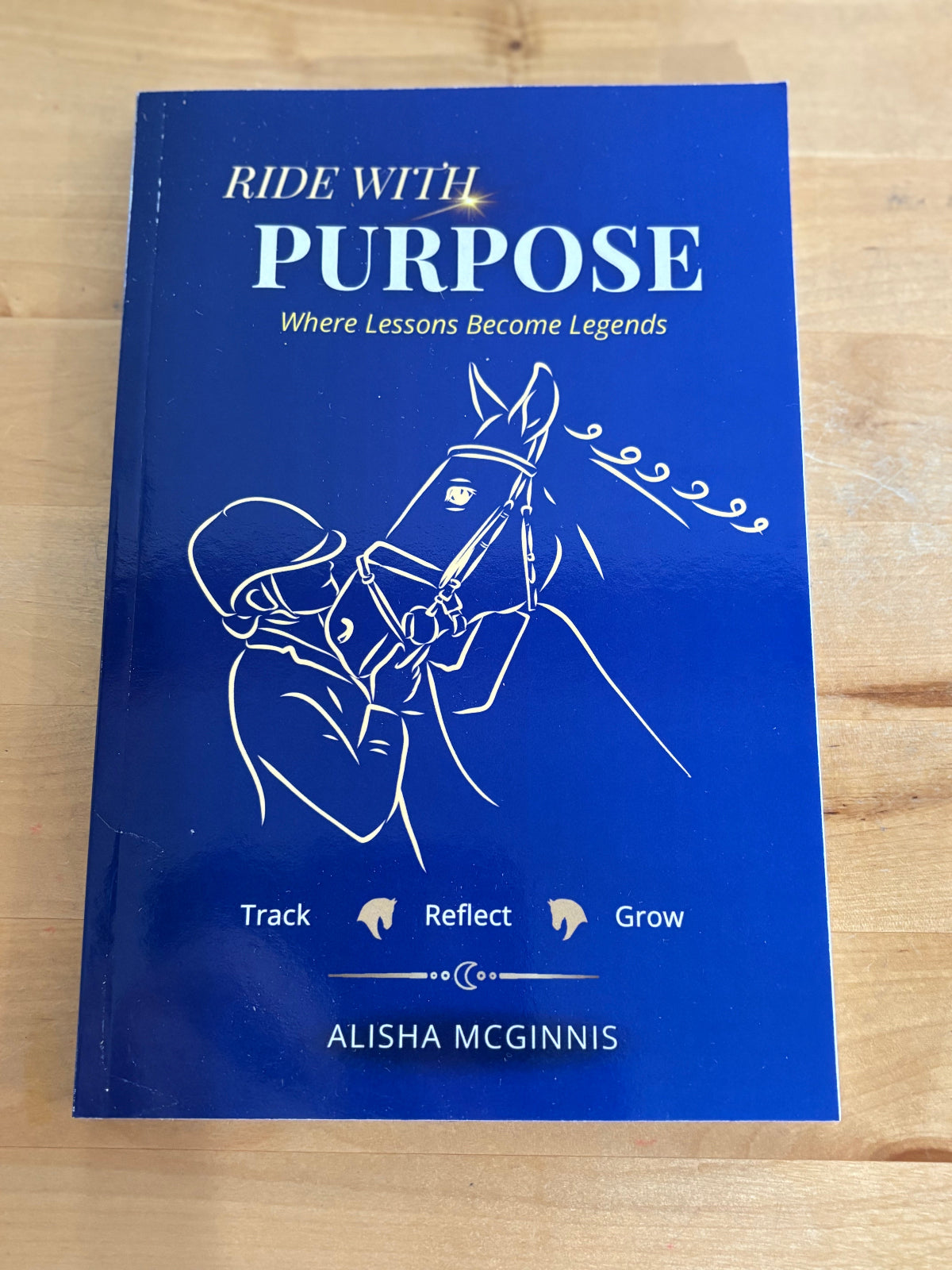 Blue book titled 'Ride with Purpose' on a wooden surface