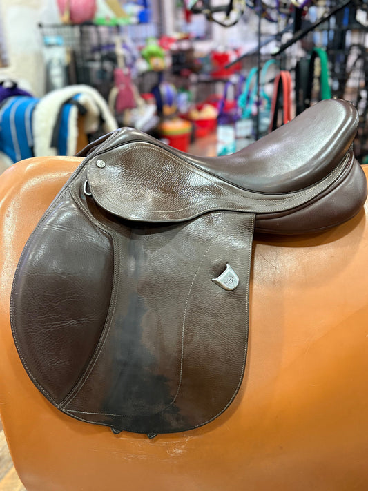 Brown leather english saddle on a stand with a store background