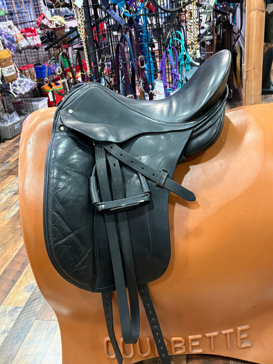 Black leather dressage saddle with stirrups shown on a stand in a tack shop. 