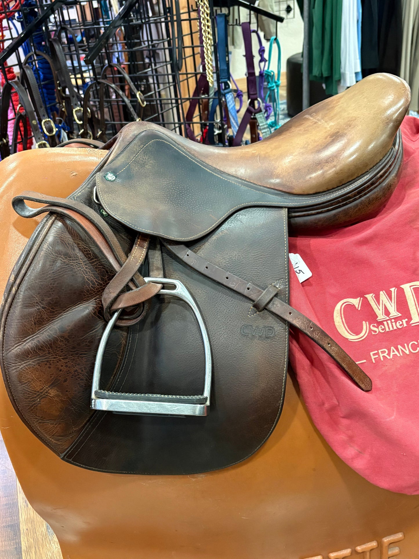 A side view of an English hunter saddle with a run up stirrup on a stand.