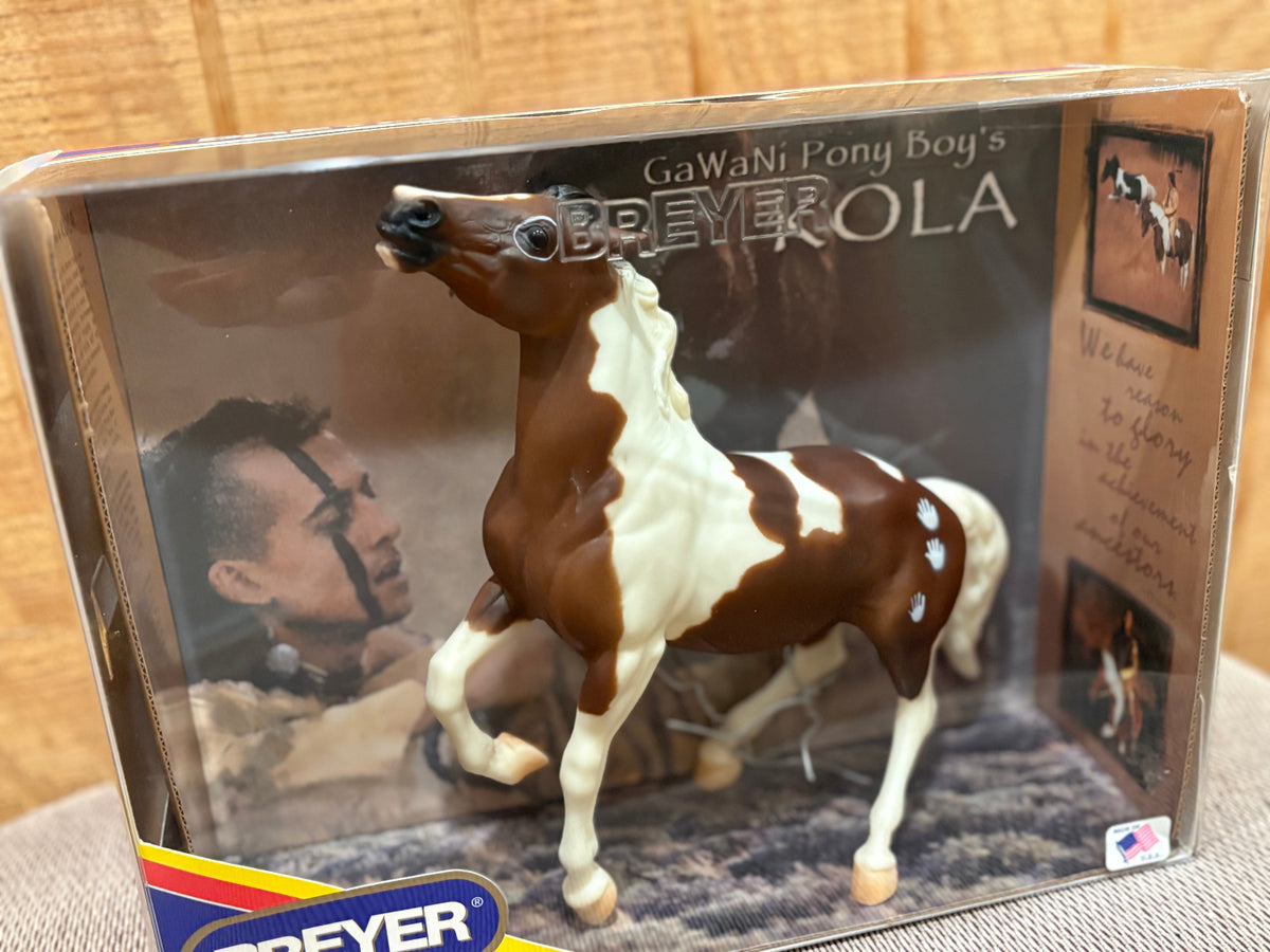 Breyer GaWaNi Pony Boy's Kola toy horse figurine in its original packaging, displayed on a neutral surface with a wooden background.