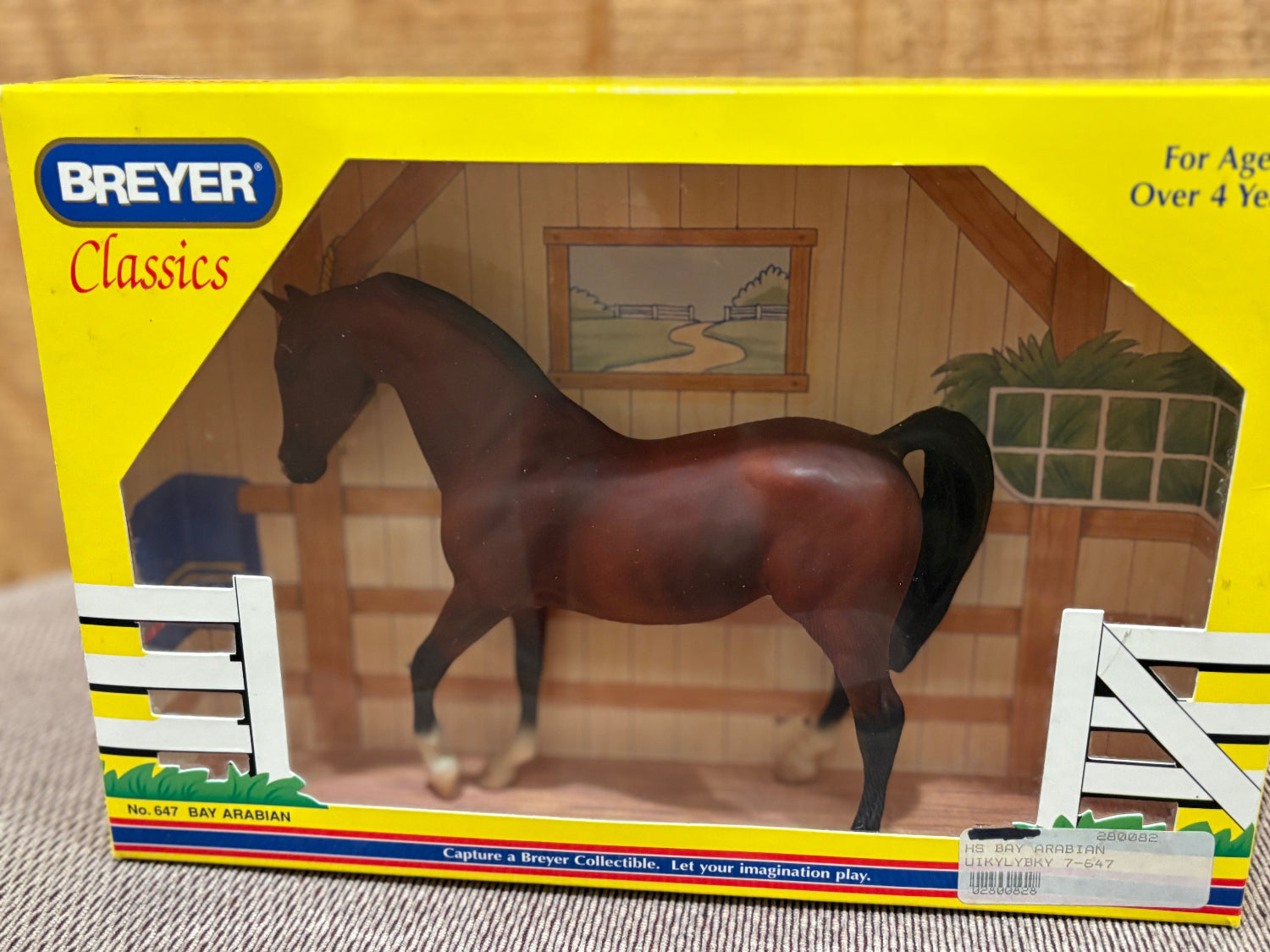 Breyer Classics model horse Bay Arabian in its original yellow window box packaging, showing a glossy brown horse inside an illustrated stable.