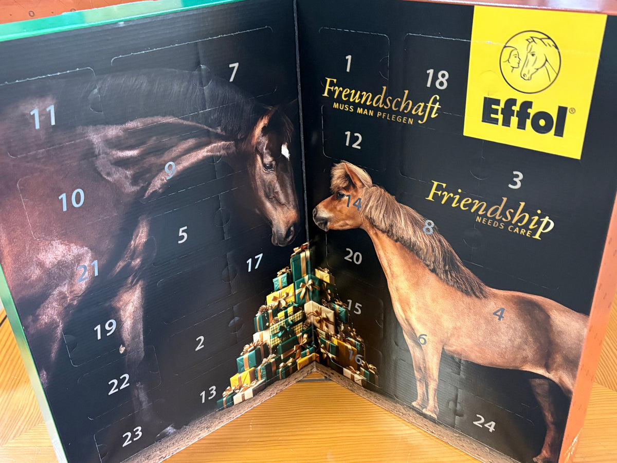 An open advent calendar featuring two horses on a black background, numbered compartments, and a yellow square logo in the top right that reads 'Effol'.