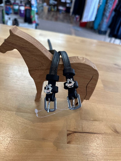 black leather equestrian spur straps with silver buckles with black, tan, and silver ninja charms resting on wooden horse model