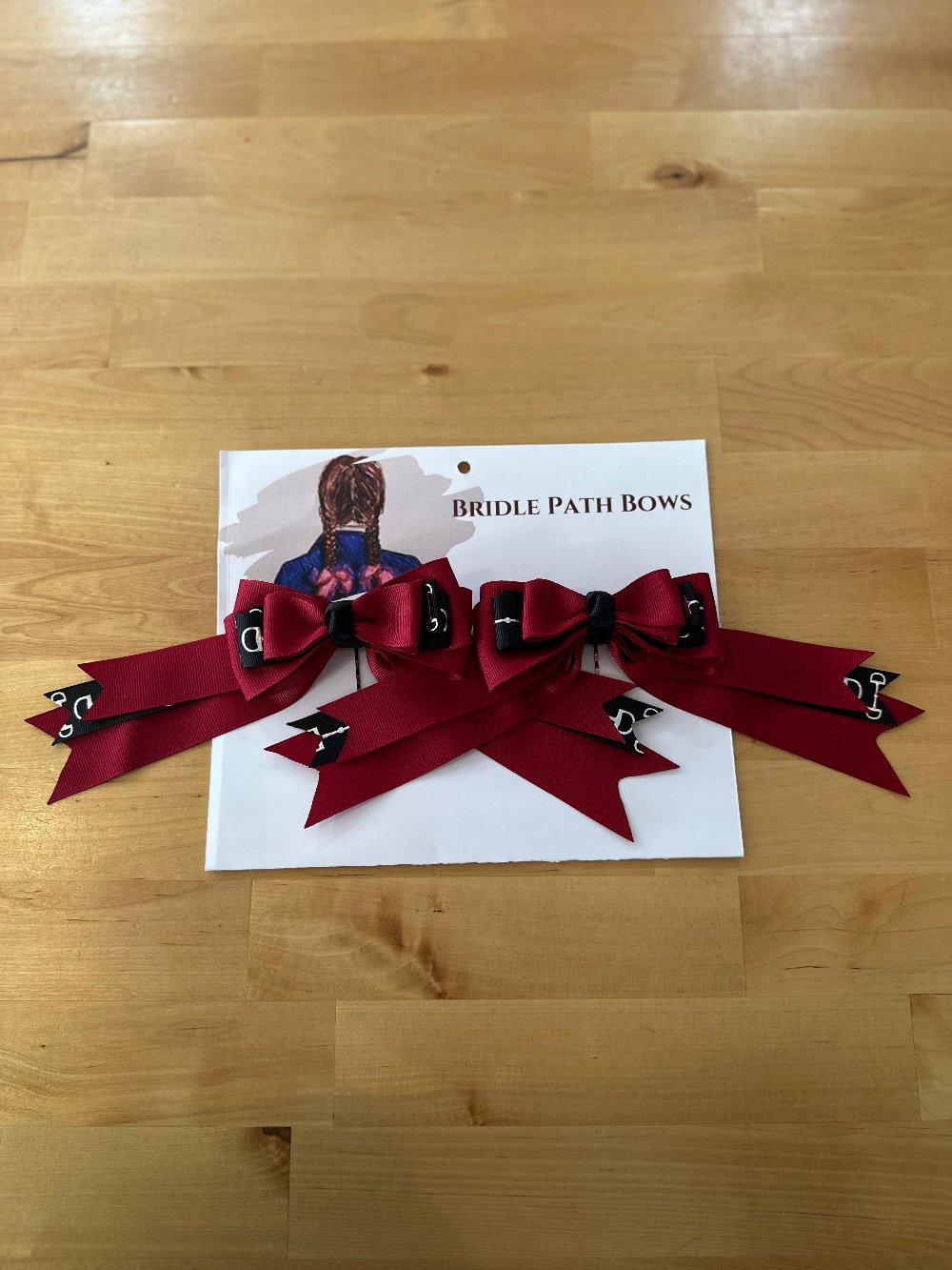 Image of children’s horse riding show bows, red and black with silver stirrup pattern