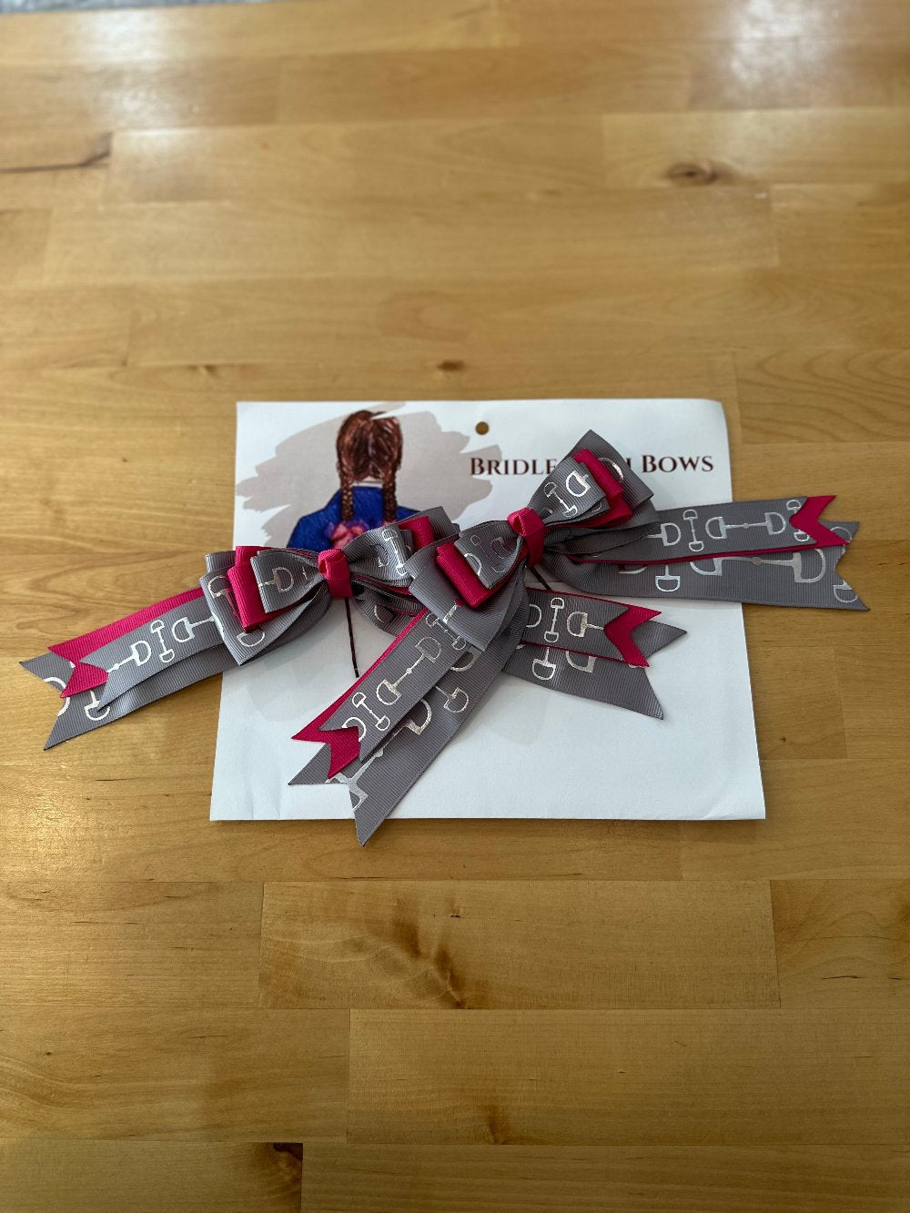 Image of children’s horse riding show bows, gray and pink with silver stirrup design