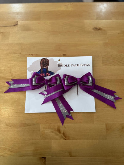 Image of children’s horse riding show bows, purple and gray with silver stirrup design