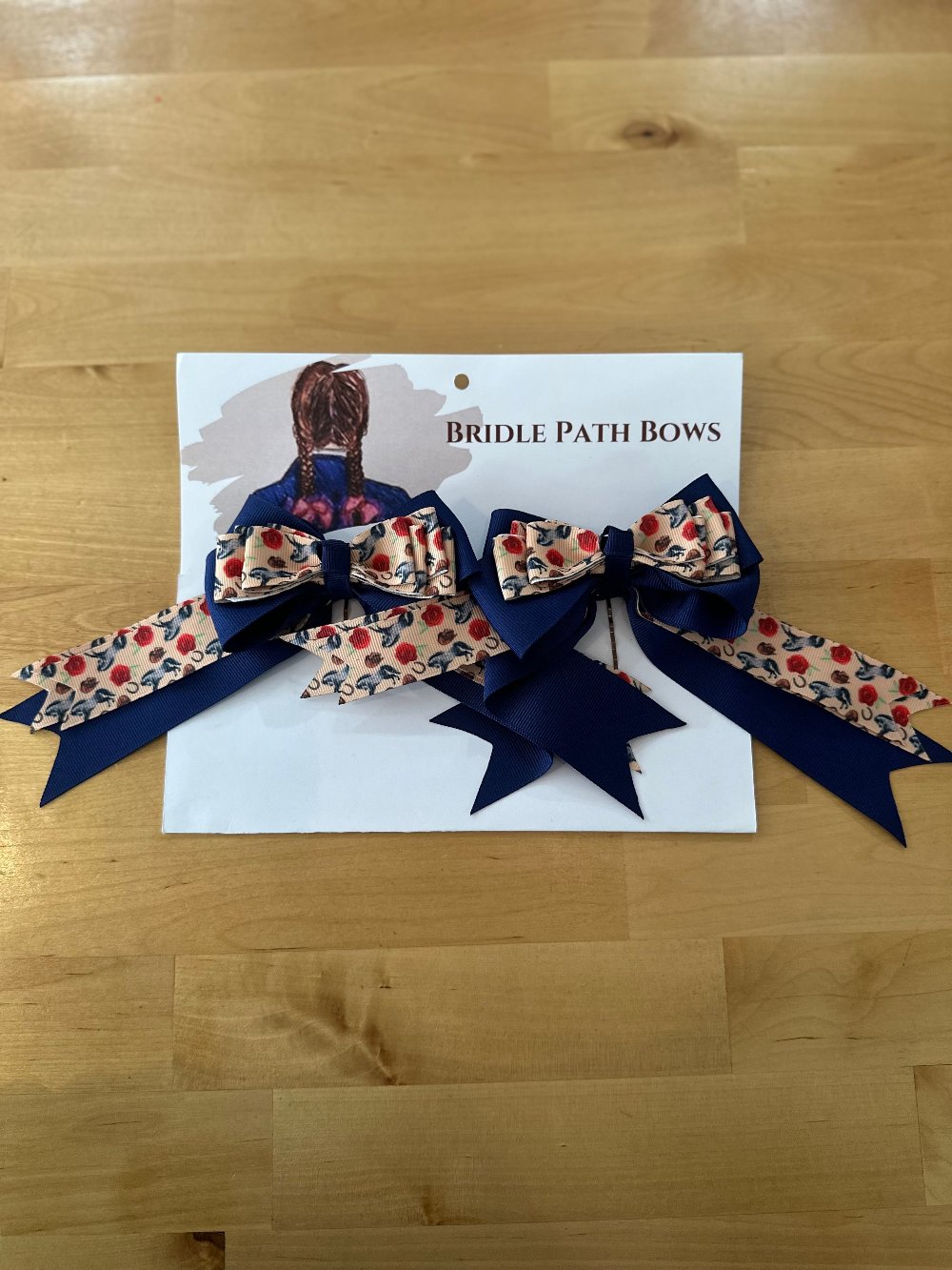 Image of children’s horse riding show bows, tan and blue with red roses and horse pattern