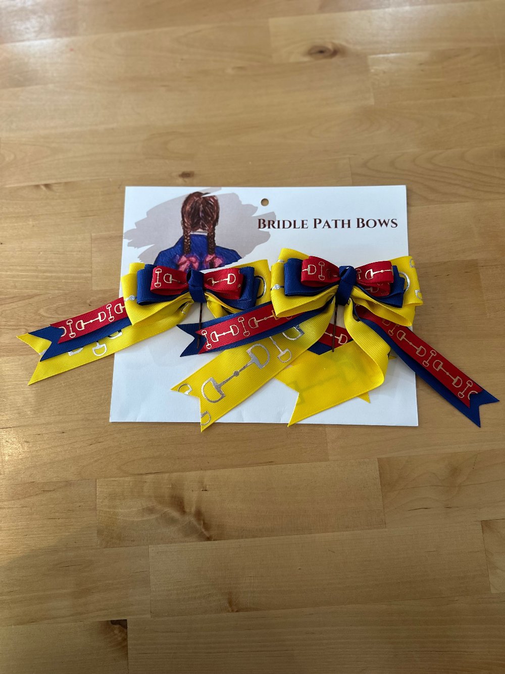 Image of children’s horse riding show bows, yellow red and blue with silver bit pattern