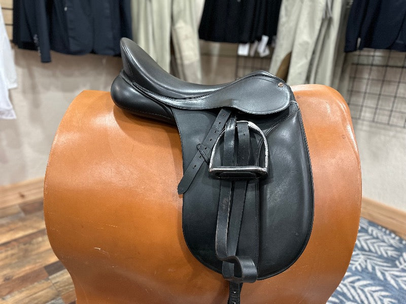 Black leather english saddle showing silver stirrups run up on black stirrup leathers.  Sitting on a tan stand.  