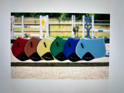 multiple saddle pads of different colors hung on a fence railing.  